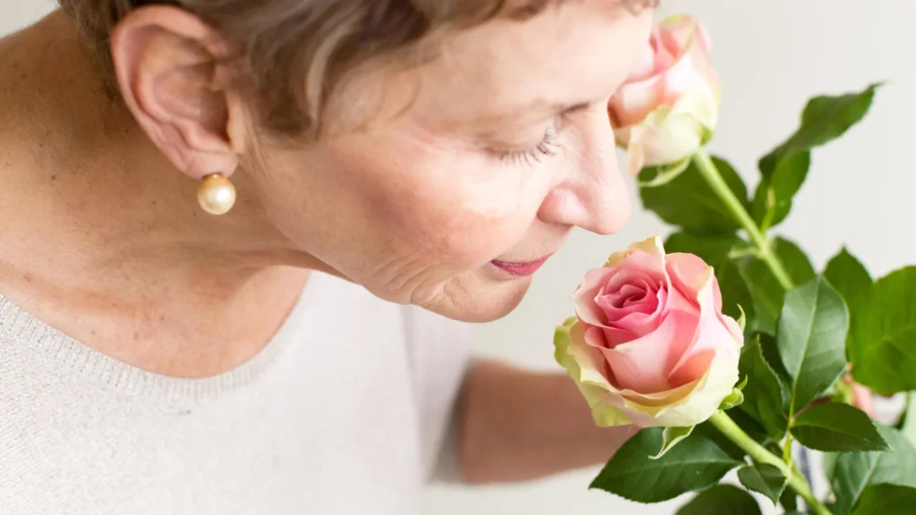 senior woman smelling pink rose.webp.webp