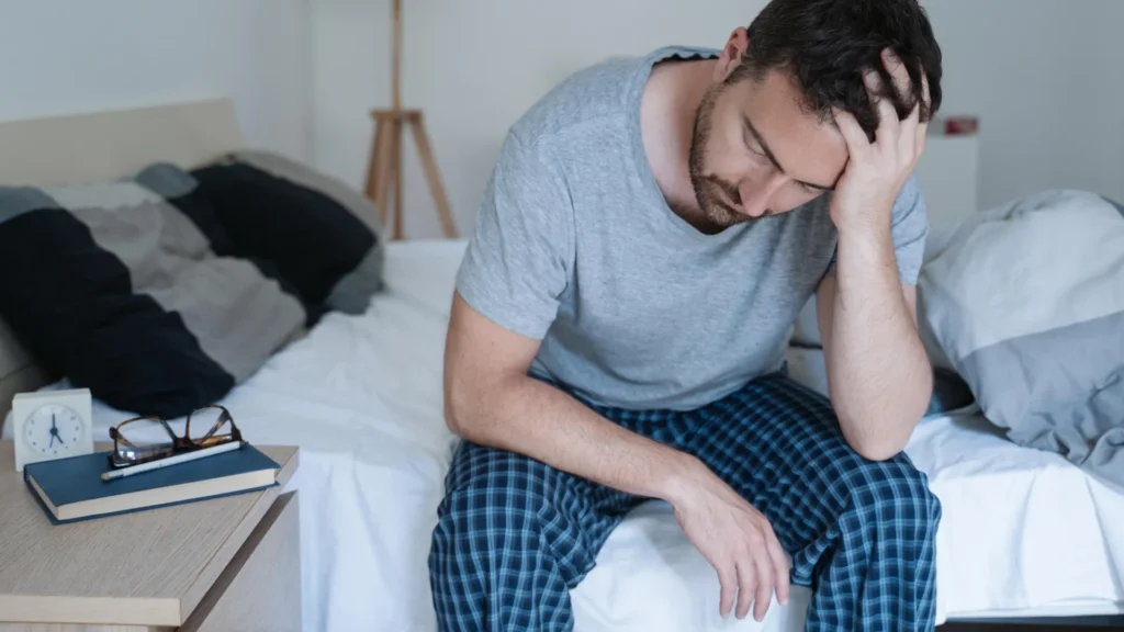 Tired Man Waking Up Early With Headache.webp 1024x576
