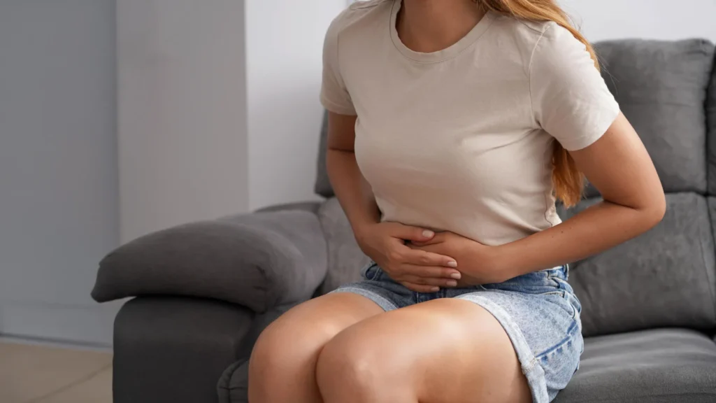 Woman On Sofa Stomach Pain Ibs Constipation.webp 1024x576